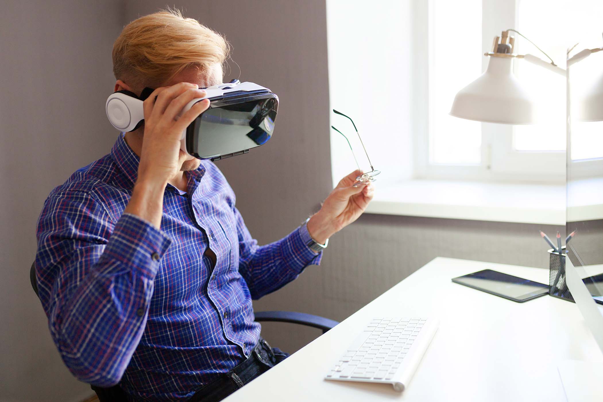 Side view of businessman in office wearing VR headset at workplace.